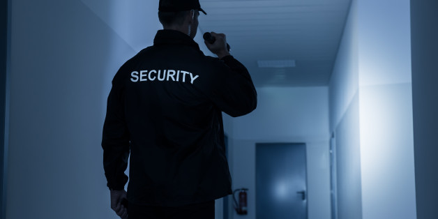 Rear view of security guard with flashlight in building corridor