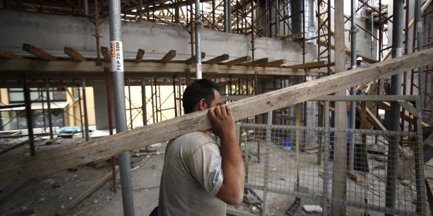A construction worker carries timber on the site of a residential housing development in the Glyka Nera suburb of Athens, Greece, on Monday, Sept. 6, 2010. Greece still faces a 'substantial' default risk as insolvency prevents the nation from repaying its debt when its bailout program expires in three years. Photographer: Kostas Tsironis/Bloomberg via Getty Images