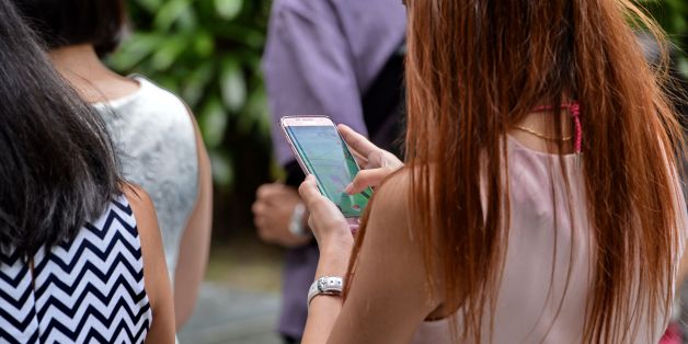 A woman plays Pokemon Go while walking along the pavement in Singapore on August 11, 2016.Pokemon Go was available in nine countries on August 6, including Singapore. / AFP / ROSLAN RAHMAN (Photo credit should read ROSLAN RAHMAN/AFP/Getty Images)