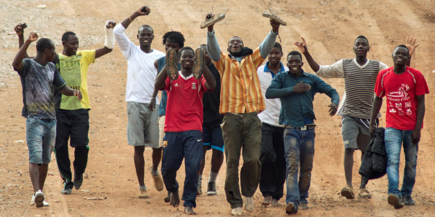 Migrants sit on the ground in El Tarajal, Ceuta, close to the boarder with Morocco on December 9, 2016 after being rounded up by police to be attended to by Red Cross personnel and taken to the Center for Temporary Stay of Immigrants (CETI) after nearly 400 migrants forced their way through a fence between Morocco and the tiny Spanish enclave of Ceuta, slightly injuring two police officers, authorities said. / AFP / Antonio SEMPERE (Photo credit should read ANTONIO SEMPERE/AFP/Getty Image