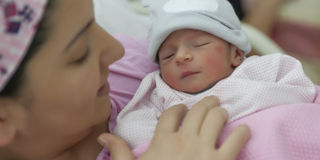 A newborn baby enters the world and mother holding newborn baby girl in the hospital.