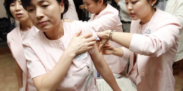 Medical workers (L) of Soon Chun Hyang University Hospital receive H1N1 flu vaccines from their colleagues at the hospital in Seoul October 27, 2009. The first round of a government vaccination program started on Tuesday for those highly vulnerable to the disease including medical staff while 25 South Koreans have died since the flu outbreak, local media reported. REUTERS/Jo Yong-Hak (SOUTH KOREA DISASTER HEALTH IMAGES OF THE DAY)