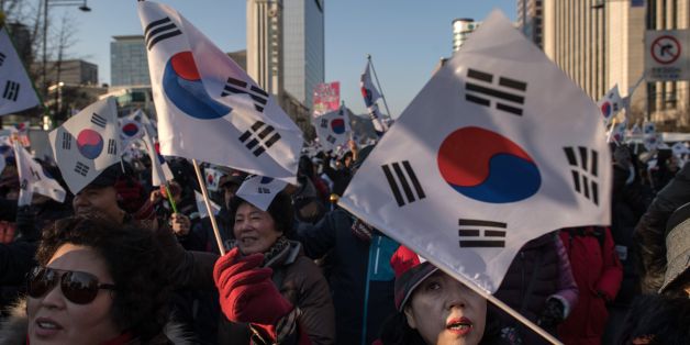 Pro-government activists shout slogans and wave flags as they stage a rally in central Seoul on February 25, 2017.South Korea's Constitutional Court will hold its final impeachment hearing to rule on the fate of President Park Geun-Hye at the end of the month, Yonhap News Agency reported February 22. / AFP / Ed JONES (Photo credit should read ED JONES/AFP/Getty Images)