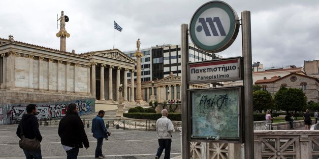 People walk past a closed Metro station during a 48-hour strike in Athens on May 22, 2016. Greece on May 22 was set to adopt fresh cuts and tax hikes ahead of a Eurogroup meeting that is expected to unlock desperately-needed bailout funds for the debt-ridden nation. After waves of protests over a string of unpopular reforms, lawmakers from the ruling leftist party are to approve the late evening of May 22 a bill of over 7,000 pages that raises the sales tax cap and introduces a mechanism to fur