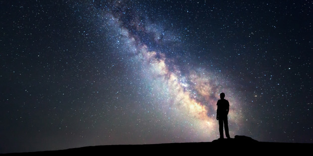 Landscape with Milky Way. Night sky with stars and silhouette of a standing happy man on the mountain.