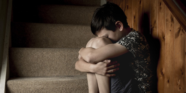 Sad, bullied or abused boy crying sitting on stairs