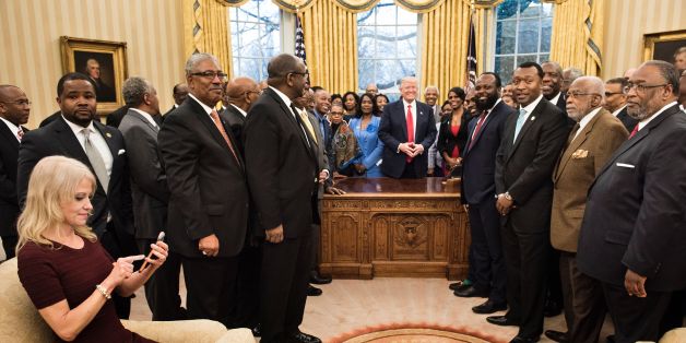 TOPSHOT - Counselor to the President Kellyanne Conway (L) checks her phone after taking a photo as US President Donald Trump and leaders of historically black universities and colleges pose for a group photo in the Oval Office of the White House before a meeting with US Vice President Mike Pence February 27, 2017 in Washington, DC. / AFP / Brendan Smialowski (Photo credit should read BRENDAN SMIALOWSKI/AFP/Getty Images)