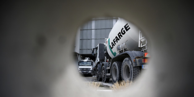 A concrete mixing truck is seen through a hole in a wall at Lafarge concrete production plant in Pantin, outside Paris, April 7, 2014. Switzerland's Holcim unveiled a deal to buy France's Lafarge on Monday to create the world's biggest cement maker, with $44 billion of annual sales, and spark a raft of asset sales worldwide to steer it through antitrust rules. REUTERS/Christian Hartmann (FRANCE - Tags: BUSINESS CONSTRUCTION)