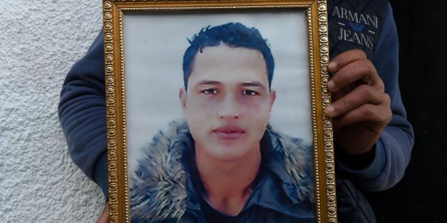 Walid Amri (back), the brother of 24-year-old Anis Amri, the prime suspect in Berlin's deadly truck attack, poses with a portrait of his brother in front of the family house in the town of Oueslatia, in Tunisia's region of Kairouan on December 23, 2016.The Islamic State group said that the man shot dead by Italian police near Milan carried out the deadly truck attack on a Berlin Christmas market. Amaq said that 'a soldier of the Islamic State' had carried out the attack 'in response to appeals t