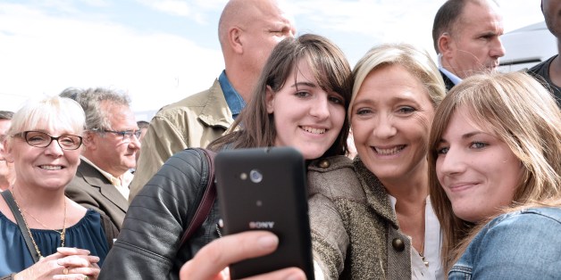 French far-right National Front (Front National, FN) party President Marine Le Pen, poses in a selfie photographs with young people as she arrives at the 28th International Livestock Trade Fair (SPACE, Salon international des Productions Animales) outside Rennes, northwestern France, on September 17, 2015. AFP PHOTO / JEAN FRANCOIS MONIER (Photo credit should read JEAN-FRANCOIS MONIER/AFP/Getty Images)