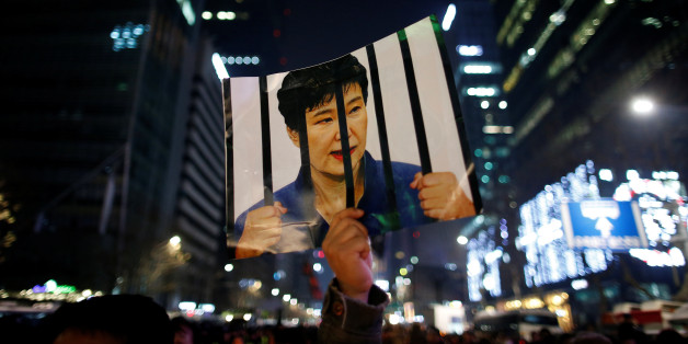 A man holds up a picture bearing an image of South Korean President Park Geun-hye as he attends a ceremony to celebrate the new year after a protest demanding Park's resignation, in Seoul, South Korea, December 31, 2016. REUTERS/Kim Hong-Ji
