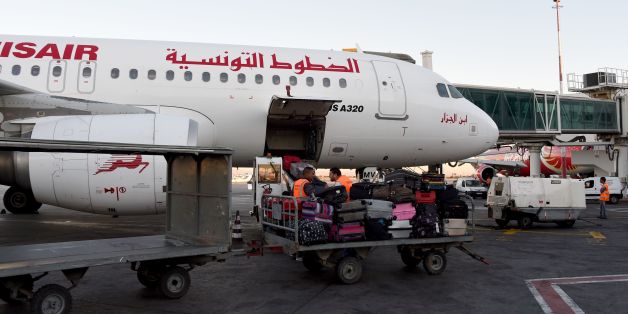 A picture taken on July 19, 2016 at Tunis-Carthage International Airport shows a labourer transporting luggage next to a Tunisair plane. / AFP PHOTO / FETHI BELAID (Photo credit should read FETHI BELAID/AFP/Getty Images)
