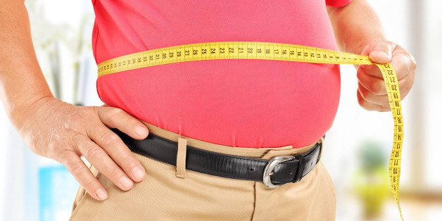 Close-up on a man measuring his belly at home