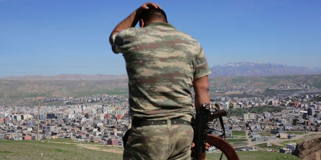 TOPSHOT - A Turkish soldier gestures while standing on the hill overlooking damaged buildings following heavy fighting between government troops and Kurdish fighters in the Kurdish town of Cizre in southeastern Turkey, which lies near the border with Syria and Iraq, on March 2, 2016.
Thousands in Turkey's Kurdish-majority town of Cizre started returning to their homes on March 2 after authorities partially lifted a curfew in place since December for a controversial military operation to root out separatist rebels. / AFP / YASIN AKGUL (Photo credit should read YASIN AKGUL/AFP/Getty Images)