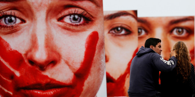 Activists talk in front photos from Brazilian photographer Marcio Freitas, during a protest by non-governmental organization (NGO) Rio de Paz (Rio of Peace) against rape and violence against women on Copacabana beach in Rio de Janeiro, Brazil, June 6, 2016. REUTERS/Sergio Moraes EDITORIAL USE ONLY.