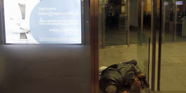 A homeless man sleeps inside the withdrawal area of a bank in downtown Milan February 9, 2012. Sub-freezing winter weather temperatures continued to hit Europe. REUTERS/Stefano Rellandini (ITALY - Tags: ENVIRONMENT SOCIETY POVERTY)