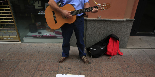 Unemployed Paco, 51, plays his guitar as he ask for alms in the Andalusian capital of Seville, southern Spain June 17, 2013. Spain's economy may show a clear turnaround in the second quarter according to available economic data, Treasury Minister Cristobal Montoro said on Monday during a conference in the northern city of Santander. The placard reads, "My last round, thanks Rajoy". REUTERS/Marcelo del Pozo (SPAIN - Tags: SOCIETY BUSINESS)