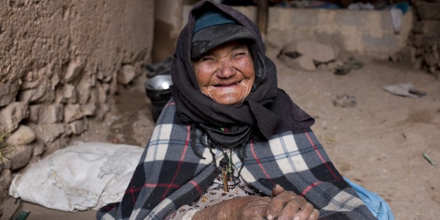 A woman smiles as she warms herself around a fire in her home in Tilmi village in the High Atlas region of Morocco February 13, 2015. The snowy foothills of the High Atlas mountains in Morocco are home to several Berber villages where the inhabitants make their living by farming, baking bread in traditional ovens, herding cattle, and the making and selling of honey, olive oil and pottery. Extreme weather fluctuations and erosion that causes flooding and landslides have led to a drop in agricultu