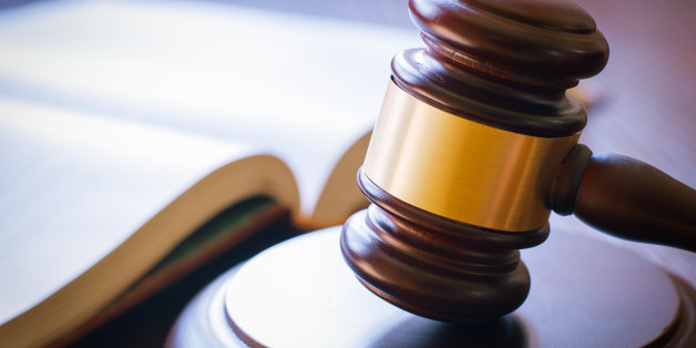 brown gavel and open book on a wooden table of the law in the courtroom