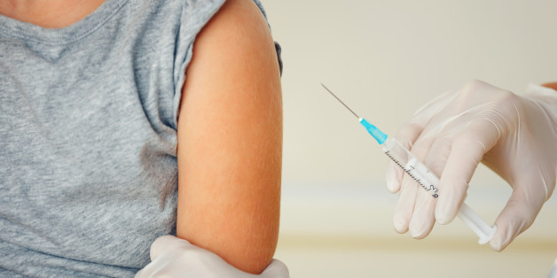 Doctor vaccinating small redhead girl.