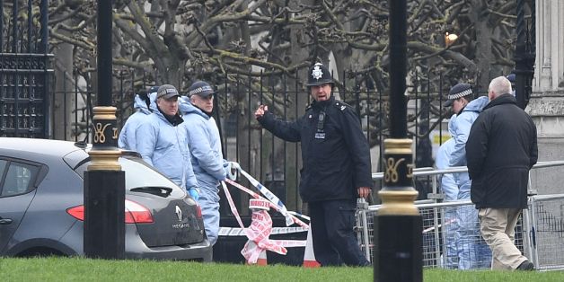 Police officers in forensics suits work at the scene on March 23, 2017 where the car collided with the gates of the Houses of Parliament during the March 22 terror attack in Westminster in central London. Britain's parliament reopened on Thursday with a minute's silence in a gesture of defiance a day after an attacker sowed terror in the heart of Westminster, killing three people before being shot dead. Sombre-looking lawmakers in a packed House of Commons chamber bowed their heads and police of