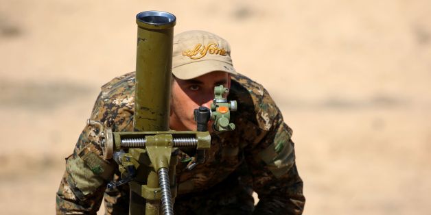 A fighter from the US-backed Syrian Democratic Forces (SDF), made up of an alliance of Arab and Kurdish fighters, prepares to fire a mortar launcher in the village of Sabah al-Khayr on the northern outskirts of Deir Ezzor as they drive to encircle the Islamic State (IS) group bastion of Raqa on February 21, 2017.The SDF made a major incursion into the oil-rich province of Deir Ezzor as part of their push for Raqa, field commander Dejwar Khabat said. / AFP / DELIL SOULEIMAN (Photo credit