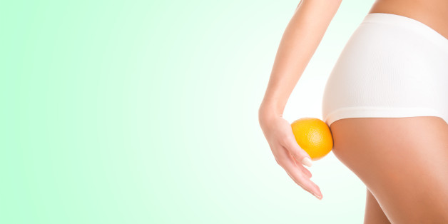 Woman holding an orange against her thighs, isolated in green