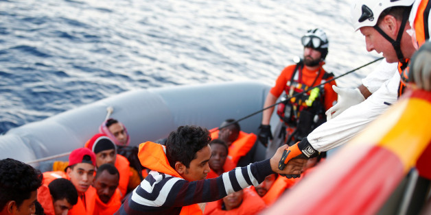 Ein Helfer des italienischen Roten Kreuzes hilft in Seenot geratenen Flüchtlingen