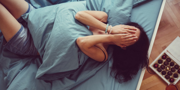 Depressed woman in bed with hands on face