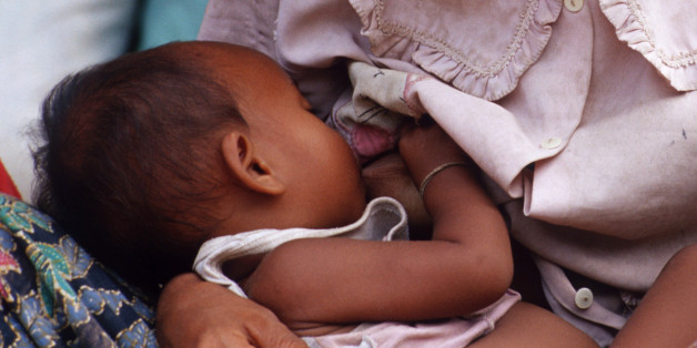 SIEM REAP, CAMBODIA - 2003/08/01: Chan Heit, 24, nurses her baby, Sey Lek who is less than a year old, as she strokes an injured pigeon. She has three kids and lives on the streets in a small community of former soldiers and homeless kids. A group of about 20 kids and adults live in a loose-knit group on the streets of Siem Reap, gateway to the world-famous temples of Angkor. Many of the adults are landmine amputees and alcoholics; many of the kids are runaways or orphans addicted to sniffing gl