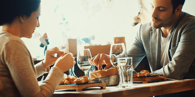 Closeup fo early 30's couple having lunch in a restaurant after shopping. Sitting by window table.They are wearing beige colored casual clothes.