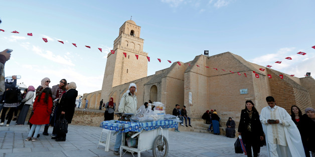 People pass a street vendor selling traditional confectioneries in front of the Uqba ibn Nafi mosque, also known as the Great Mosque, during a celebration to mark the birthday anniversary of Prophet Mohammad, in Kairouan, Tunisia December 12, 2016. REUTERS/Zoubeir Souissi
