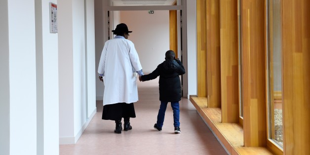 A nursing auxiliary and a child walk on March 21, 2017 in Neuilly-Plaisance, near Paris, in the new day hospital for autistic children. / AFP PHOTO / BERTRAND GUAY (Photo credit should read BERTRAND GUAY/AFP/Getty Images)