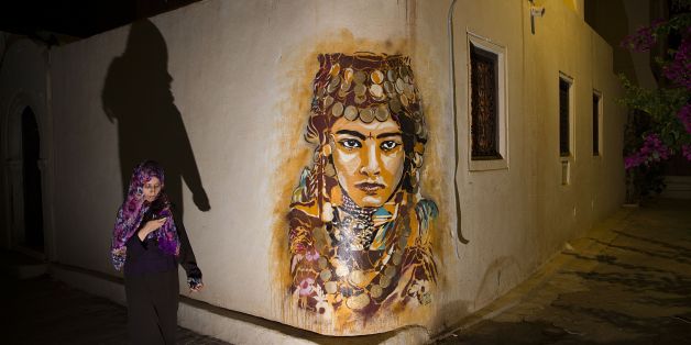 A woman walks past a mural by Spanish artist B-TOY in the village of Erriadh, on the Tunisian island of Djerba, on August 7, 2014, as part of the artistic project 'Djerbahood'. Nearly 100 artists from 30 different nationalities were invited by French-Tunisian organizer Mehdi Ben Cheikh to take part in an initiative to turn Djerba's Erriadh town into an 'open sky museum'. The village of Erriadh is one of the oldest in Tunisia where Jews, Muslims and Christians have lived together for centuries. A