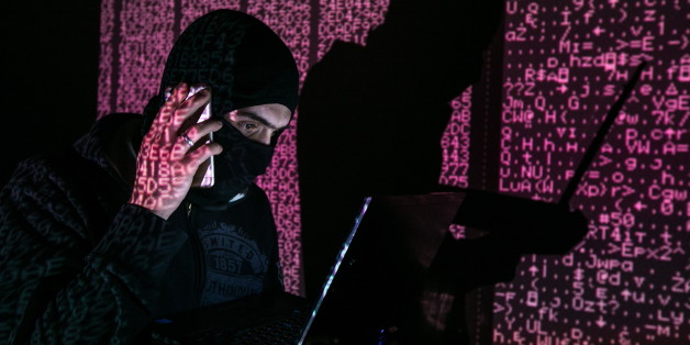 ST PETERSBURG, RUSSIA - FEBRUARY 6, 2017: A man in a balaclava mask sitting at a laptop computer, with computer code in the background. Sergei Konkov/TASS (Photo by Sergei Konkov\TASS via Getty Images)