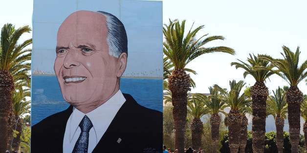 Tunisian wait next to a giant poster of former Tunisian president Habib Bourguiba as they attend an anniversary ceremony at the tomb on April 6, 2011 in Monastir. Tunisian leaders celebrate today the 11th anniversary of the death of the nation's father of independence Habib Bourguiba. AFP PHOTO/ FETHI BELAID (Photo credit should read FETHI BELAID/AFP/Getty Images)