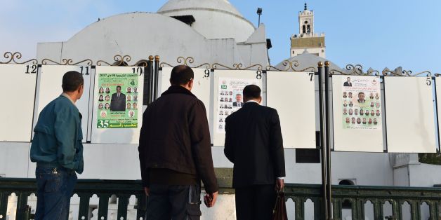 Algerian men look at electorial campaign posters for the upcoming legislative elections in Algiers' Martyrs Square as the official start of campaigning got underway on April 9, 2017. / AFP PHOTO / RYAD KRAMDI / RYAD KRAMDI (Photo credit should read RYAD KRAMDI/AFP/Getty Images)