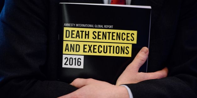 In this photo taken on April 10, 2017, a global report booklet by Amnesty International entitled 'Death Sentence and Execution' is held by James Lynch, deputy director of the Global Issues Programme at Amnesty International, after a media briefing at the Foreign Correspondents' Club (FCC) in Hong Kong. China executed more people in 2016 than all other nations combined, Amnesty International said on April 11, 2017, as death penalties in the world decreased overall. / AFP PHOTO / ANTHONY WALLACE