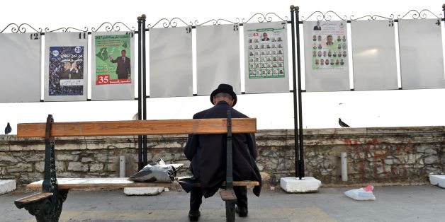 Un homme assis devant des panneaux de campagne électorale à Alger, le 9 avril 2017