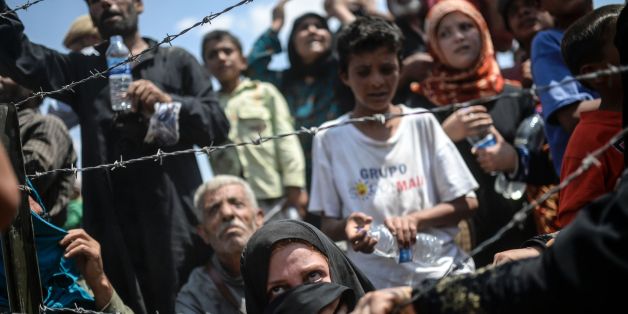 Syrians fleeing the war wait to enter Turkey near the Turkish border crossing at Akcakale in Sanliurfa province on June 15, 2015. Turkey said it was taking measures to limit the flow of Syrian refugees onto its territory after an influx of thousands more over the last days due to fighting between Kurds and jihadists. Under an 'open-door' policy, Turkey has taken in 1.8 million Syrian refugees since the conflict in Syria erupted in 2011. AFP PHOTO / BULENT KILIC / AFP / BULENT KILIC (Photo credit should read BULENT KILIC/AFP/Getty Images)
