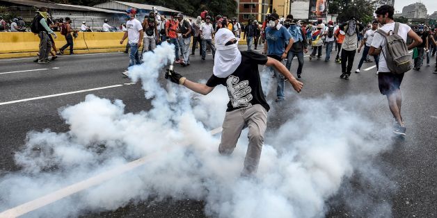 TOPSHOT - Demonstrators clash with the riot police during a protest against Venezuelan President Nicolas Maduro, in Caracas on April 20, 2017.Venezuelan riot police fired tear gas Thursday at groups of protesters seeking to oust President Nicolas Maduro, who have vowed new mass marches after a day of deadly unrest. Police in western Caracas broke up scores of opposition protesters trying to join a larger march, though there was no immediate repeat of Wednesday's violent clashes, which left three