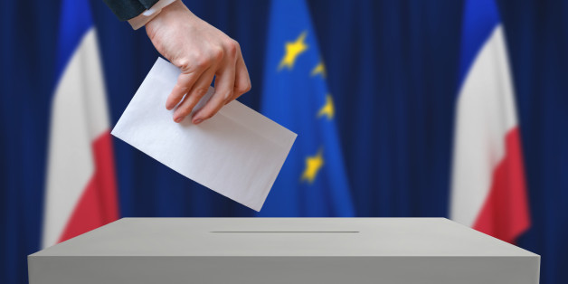Election in France. Voter holds envelope in hand above vote ballot. French and European Union flags in background.