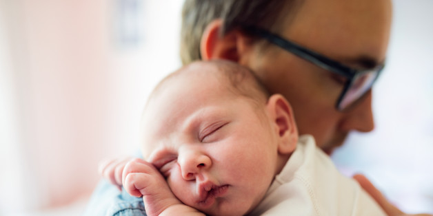 Close up of young father holding his newborn baby son in his arms