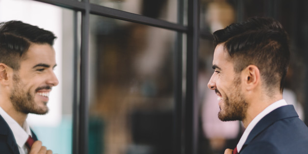Smiling businessman fixing his necktie before going out