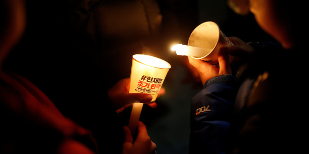 A child lights a candle during a protest demanding South Korean President Park Geun-hye's resignation in Seoul, South Korea, January 7, 2017. The lettering reads: "Constitutional court should accept early impeachment". REUTERS/Kim Hong-Ji