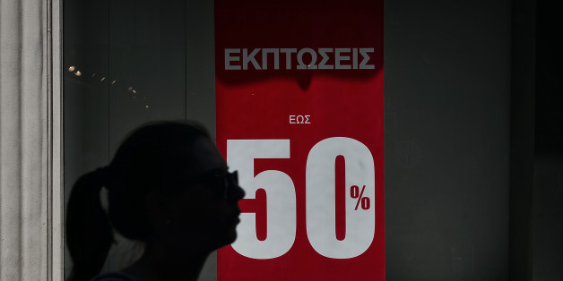 A woman walks by a shop offering summer sales on July 11, 2016 in Athens. / AFP / LOUISA GOULIAMAKI (Photo credit should read LOUISA GOULIAMAKI/AFP/Getty Images)