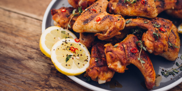 Spicy chicken wings sprinkled with chillie and herbs on a vintage wooden table