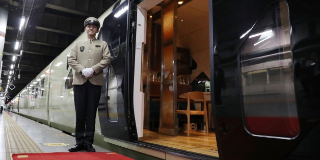 This picture taken on April 26, 2017 shows a crew member standing next to the Train Suite Shiki-Shima, operated by East Japan Railway, at Ueno Station in Tokyo during a press preview.The luxury sleeper Shiki-Shima, which can accommodate up to 34 passengers, has 10 cars, including a lounge car, a dining car and two observatory cars. The train has only 17 cabins, all suites, and the most expensive room, known as Shiki-Shima Suite, is priced at 950,000 yen (8480 USD) per person when shared by two p