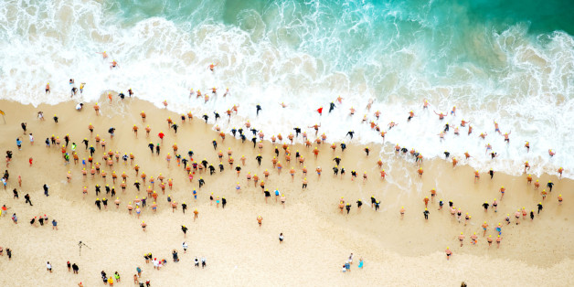 An aerial image of a group of swimming running in the the ocean at the start of a race.
