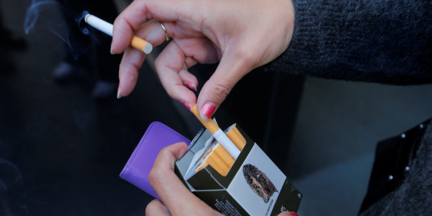 A photo illustration shows a smoker with a pack of cigarettes featuring restrictive tobacco packaging outside a Sydney office building in Australia, May 5, 2017. REUTERS/Jason Reed